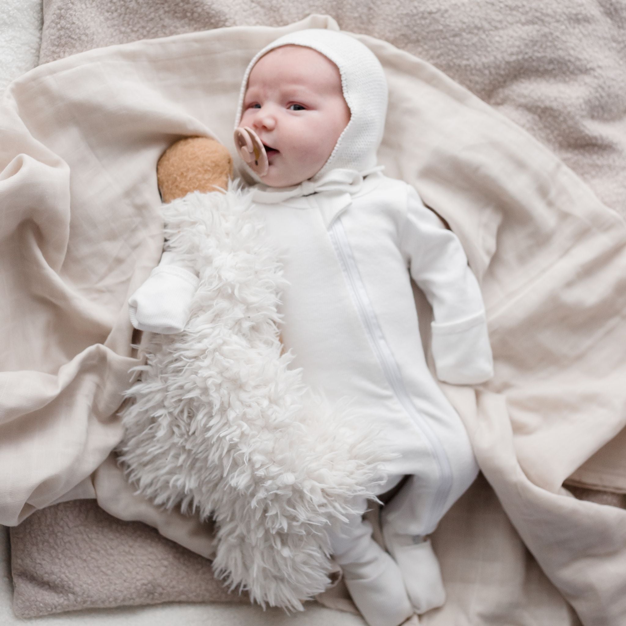 Baby laying on Muslin Swaddle Blanket | Oat (Organic)